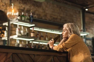 woman drinking alone at the bar, alcohol addiction
